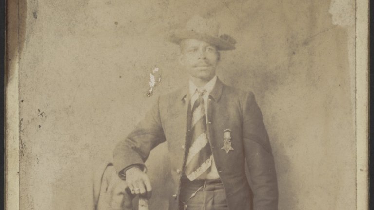 Private Fitz Lee, in a suit and hat, poses with his Medal of Honor.